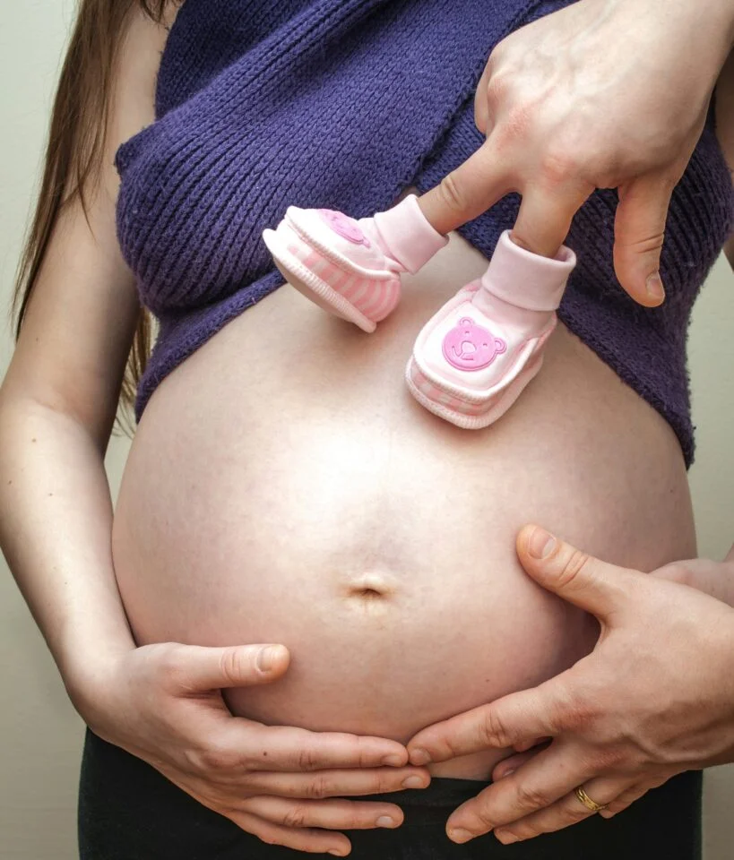 Pink shoes on pregnant belly