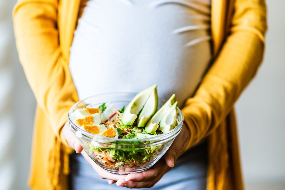 Pregnant woman holding a bowl of salad